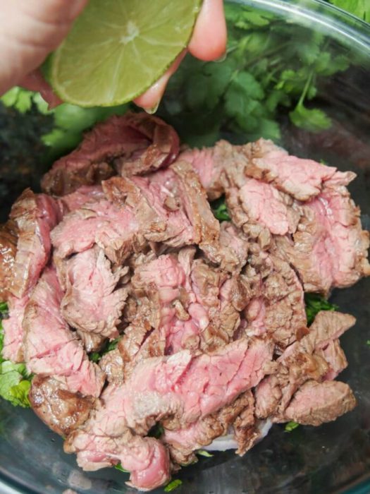 Vắt nửa quả chanh vào hỗn hợp salad bò
