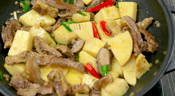 Cho thêm mùi tàu, hành lá và ớt vào nồi gân bò đảo đều